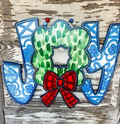 the word joy is painted in blue and green with a red bow on it's front