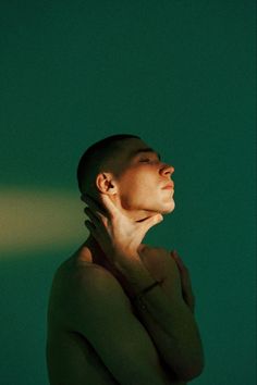 a woman with her hands on her face looking up at something in the air, against a green background