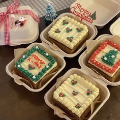 four decorated christmas cookies in plastic containers on a table