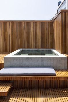 a hot tub sitting on top of a wooden deck next to a bench and stairs