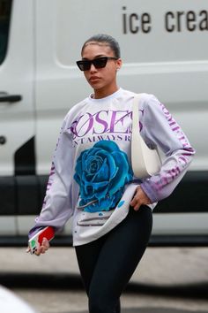 a woman in black leggings and a white shirt is walking down the street