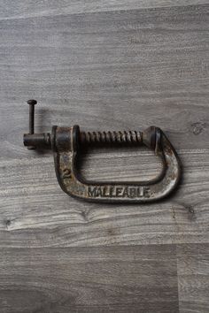 an old metal hook with the word malfait on it sitting on a wood floor