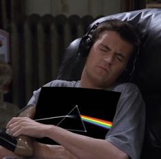 a man laying in a chair holding a laptop with the dark side of the moon on it