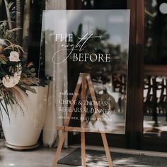 a sign that is sitting on top of a easel next to a vase with flowers