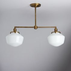 two white glass shades hang from an antique brass chandelier