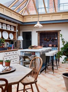 an open kitchen and dining room area with wooden tables, chairs, pots and pans hanging from the ceiling