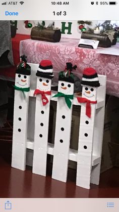 three snowmen sitting on top of white pickets