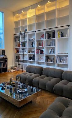 a living room filled with furniture and bookshelves next to a large glass table