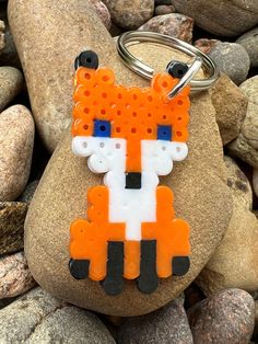 an orange and white fox keychain sitting on top of a pile of rocks