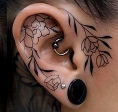 a person with tattoos on their ear and behind the ear is an ear piercing that looks like a flower