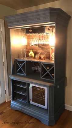 an entertainment center with wine glasses and bottles on it's glass doors, in the corner of a room