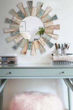 a blue desk with a mirror on the wall above it and a pink ottoman underneath