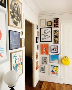 there are many framed pictures on the wall in this room with wood flooring and white walls