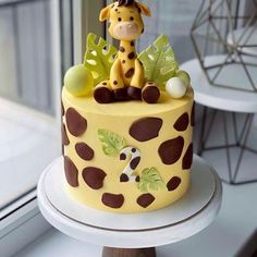 a cake decorated with a giraffe on top of a white table next to a window