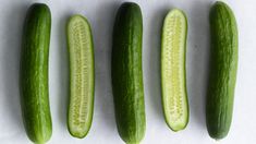 four green cucumbers lined up next to each other