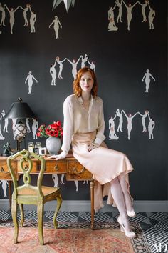 a woman sitting on top of a wooden desk