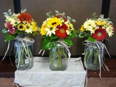 three vases with flowers in them are sitting on a white cloth and tied together