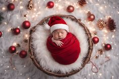 a newborn baby wrapped in a red blanket and wearing a santa hat is surrounded by christmas decorations