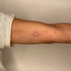 a person's arm with a small sun tattoo on the left side of their arm