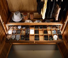 an open wooden cabinet filled with ties and hats