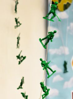 green toy soldiers are hanging from strings in front of a blue and yellow wallpaper