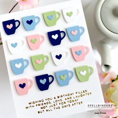 a birthday card with coffee cups and hearts on it, sitting next to some flowers