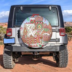 a jeep parked in the desert with an artistic design on it's tire cover