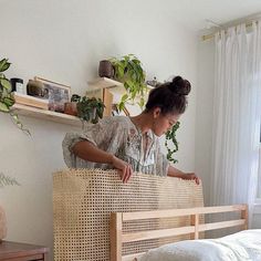 a woman standing on top of a bed next to a wooden headboard and foot board