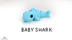 a baby shark toy laying on top of a white surface with the words baby shark written below it