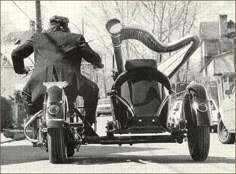 a man riding on the back of a motorcycle next to another person in a suit