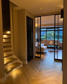 an open living room with stairs leading up to the second floor and glass doors on both sides