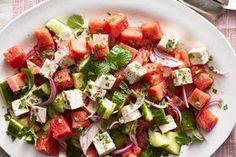 a white plate topped with cucumber, onions and tomato salad on top of a checkered table cloth