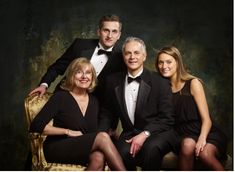 an older man and two younger women pose for a family photo in formal attire, sitting on a gold chair