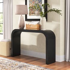 a black console table with a basket on top and a lamp in front of it