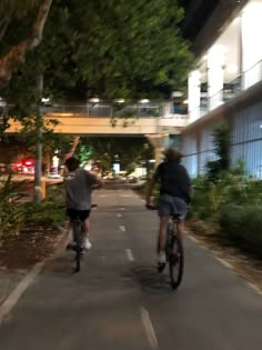 two people riding bikes down a street at night