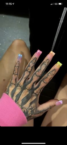 a woman's hand with tattoos on it and nails in the middle of her fingers