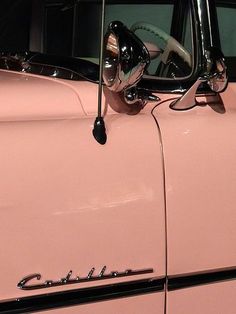 an old pink car with the hood up and mirror on it's headlight