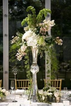 a tall vase filled with flowers on top of a table