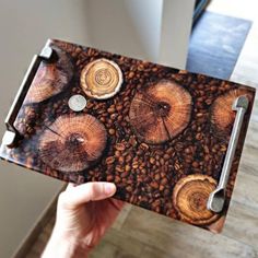 a person holding up a piece of wood that has been cut in half and is surrounded by coffee beans