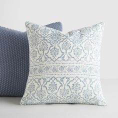 two blue and white pillows sitting next to each other