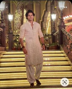 a man standing on some steps in front of stairs with lights and chandeliers