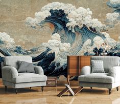 two chairs and a table in front of a wall with an ocean painting on it