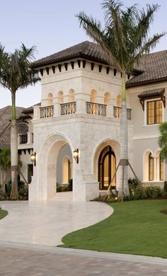 a large white house with palm trees in the front yard