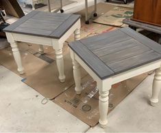 two small tables sitting on top of a piece of cardboard in a room filled with furniture