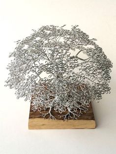 a metal tree sculpture sitting on top of a wooden stand