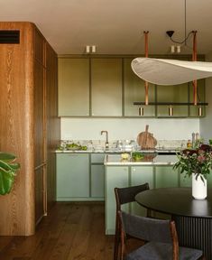 a kitchen filled with lots of green cabinets next to a dining room table and chairs