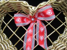 a red and silver heart shaped wreath with a bow on it's side, sitting in front of a black background