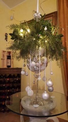 a glass table topped with a vase filled with flowers and christmas ornaments next to a wine rack