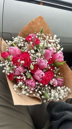 a bouquet of pink and red flowers in someone's lap