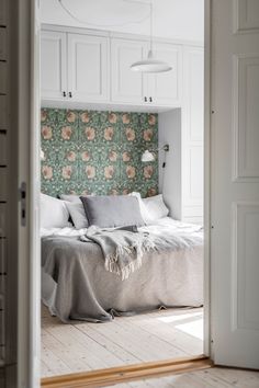 an open door leading to a bedroom with floral wallpaper